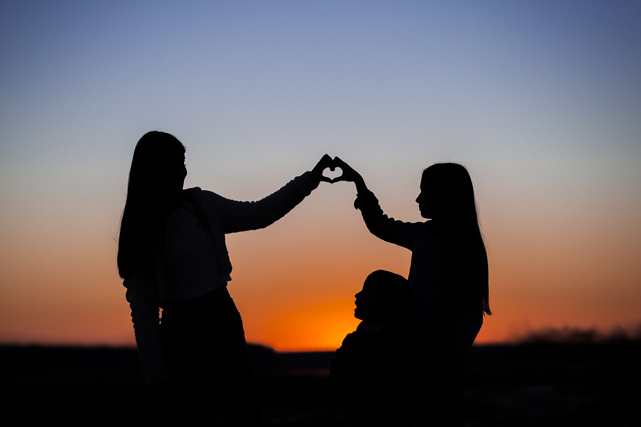 Silhouette of a couple forming a heart shape at sunset