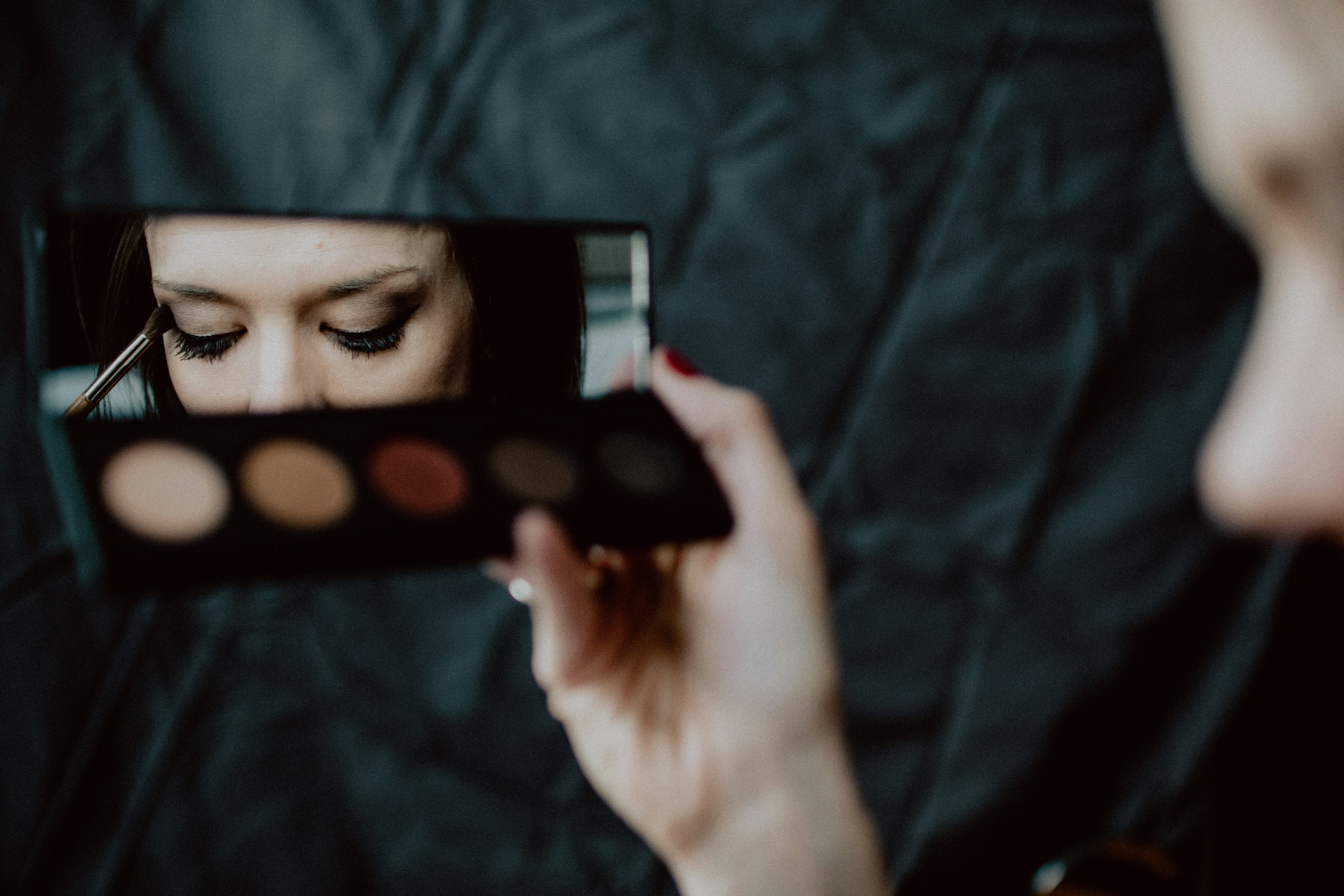 Woman applying makeup while looking in a mirror