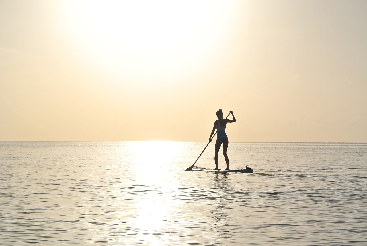 Person paddleboarding at sunrise