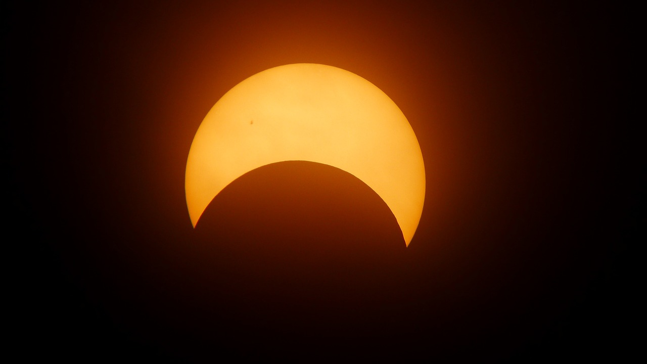 A darkened moon partially covered in shadow with a hazy glow