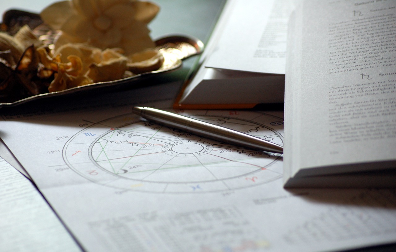 Astrological chart and pen on a desk with open books