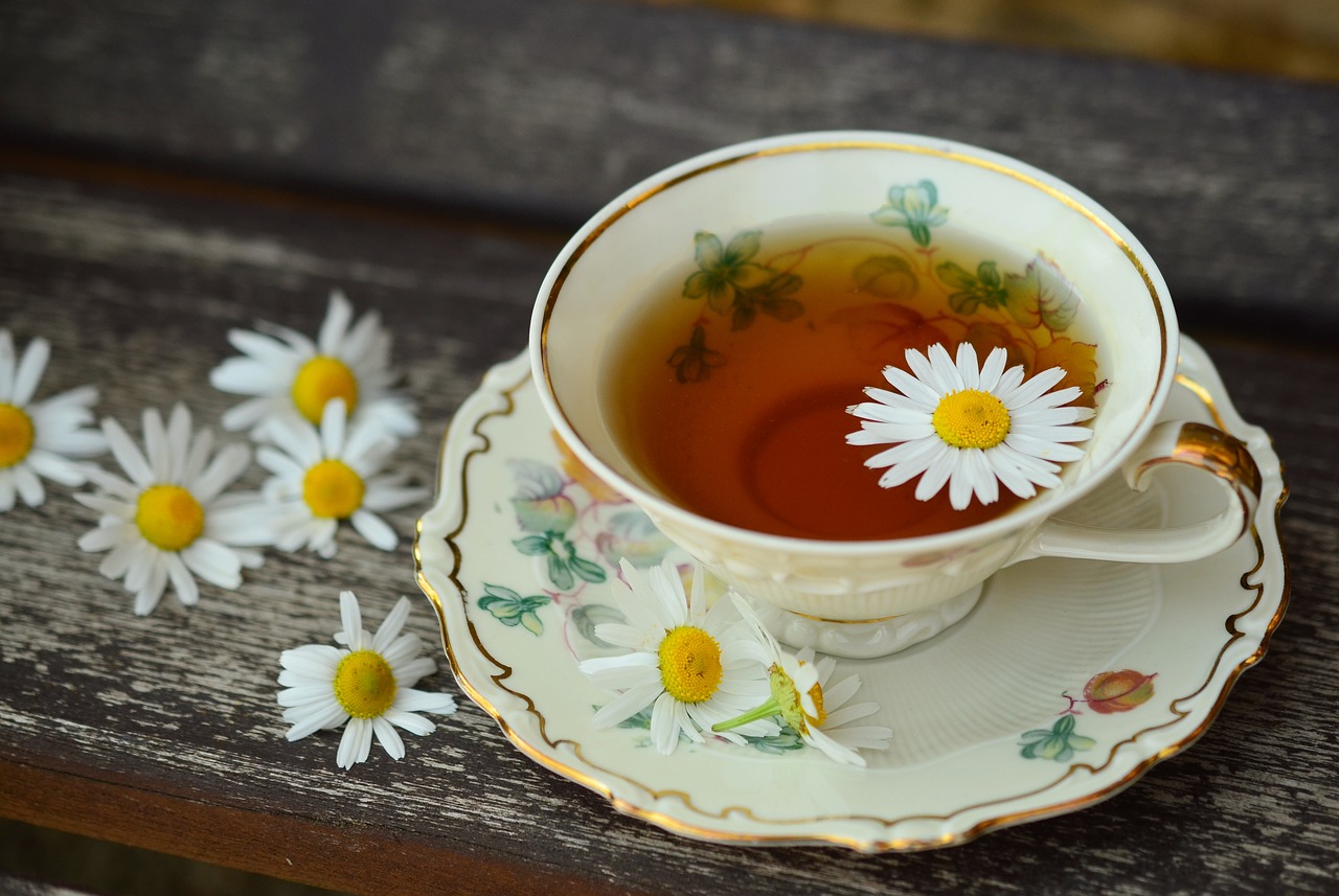 Cup of herbal tea on a wooden table with daisies