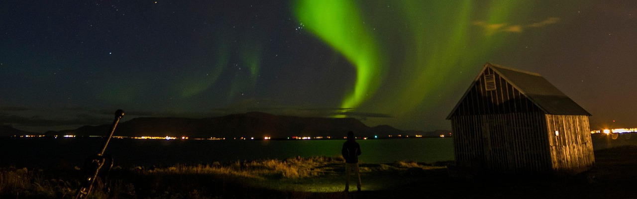 Aurora borealis in a night sky with a small cabin in the foreground