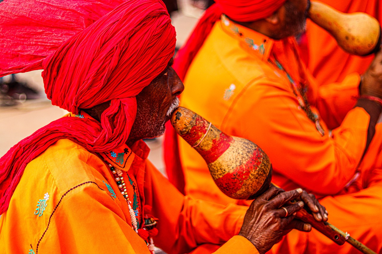 Musicians in orange traditional Indian attire playing instruments