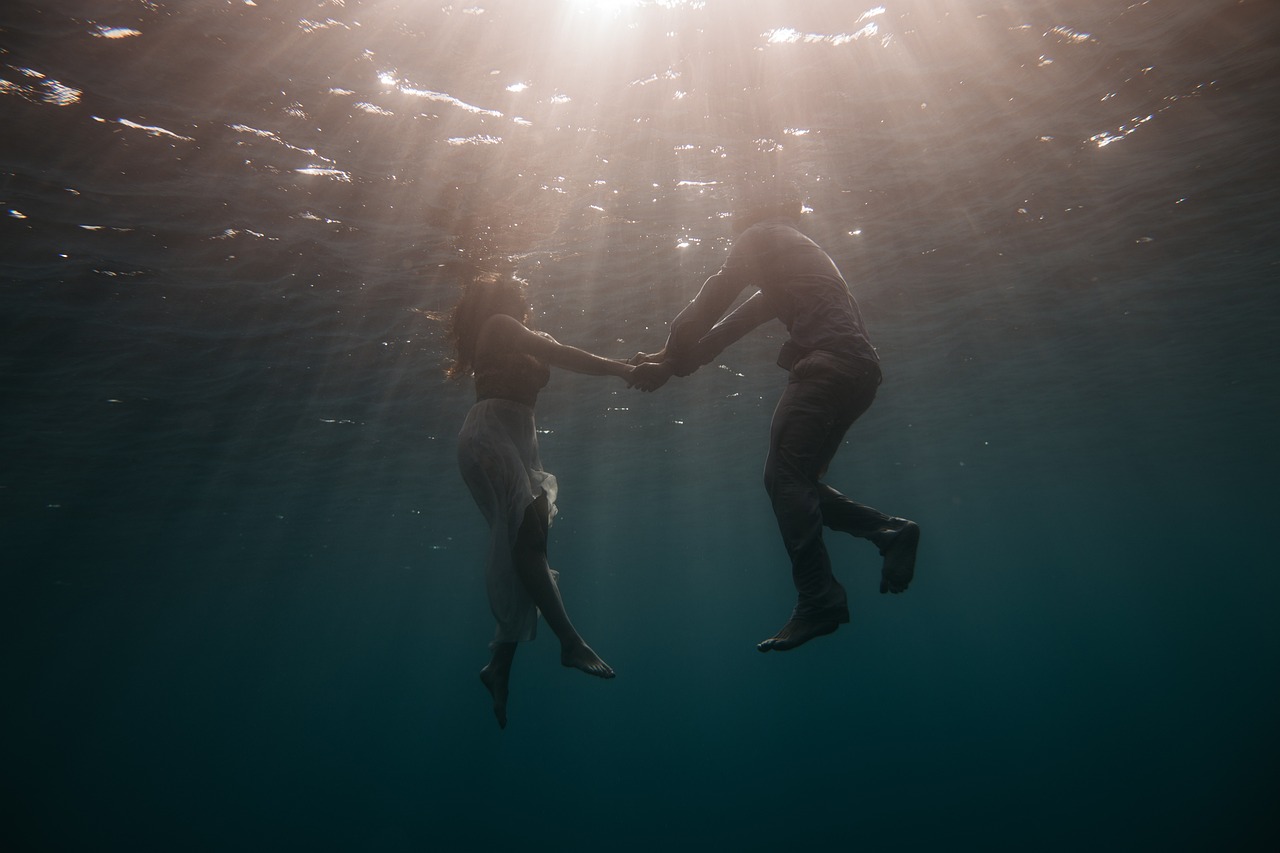 Couple holding hands underwater