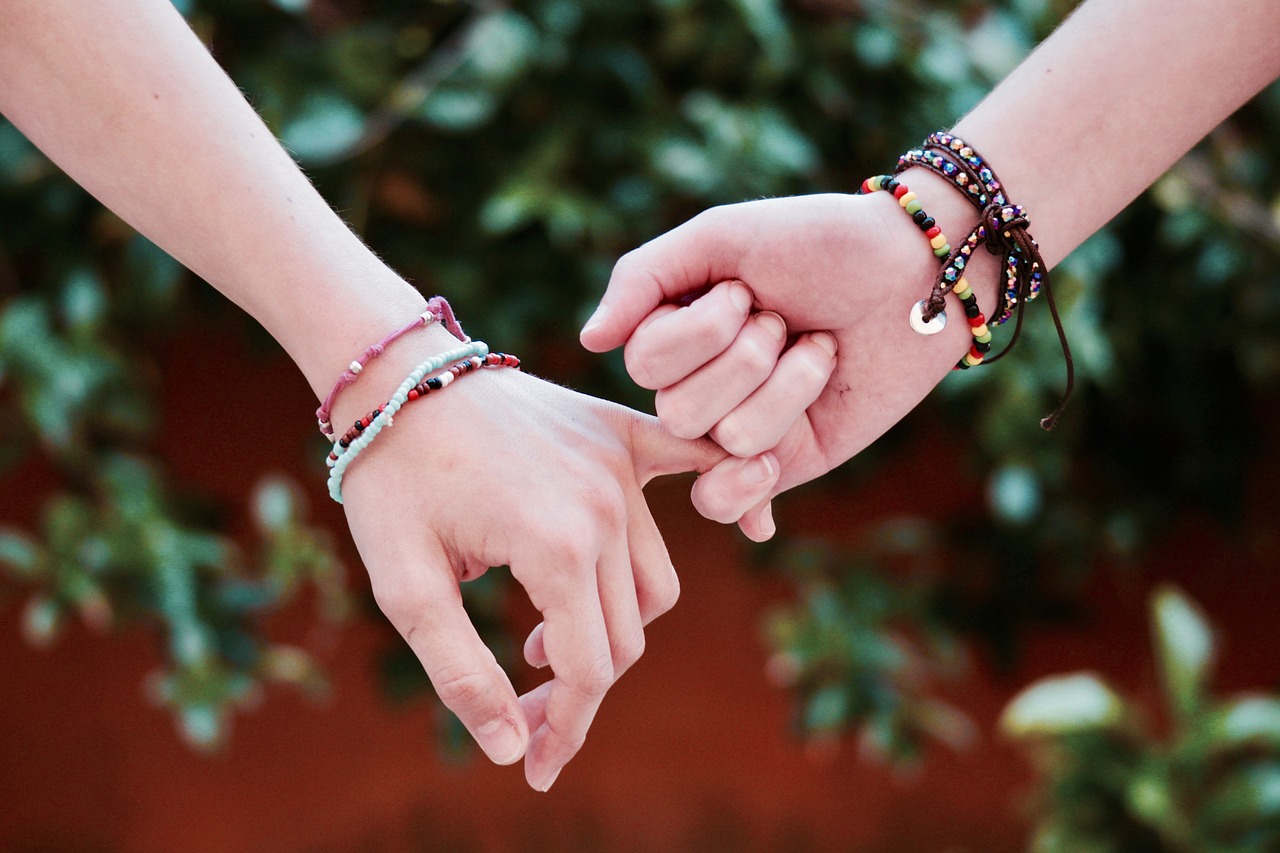 Friends holding hands with colorful bracelets