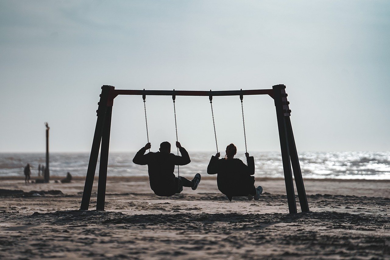 Two people swinging on a beach